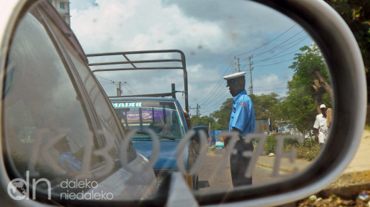 Policjant kenijskiej drogówki sprawdza samochody w kolejce na prom